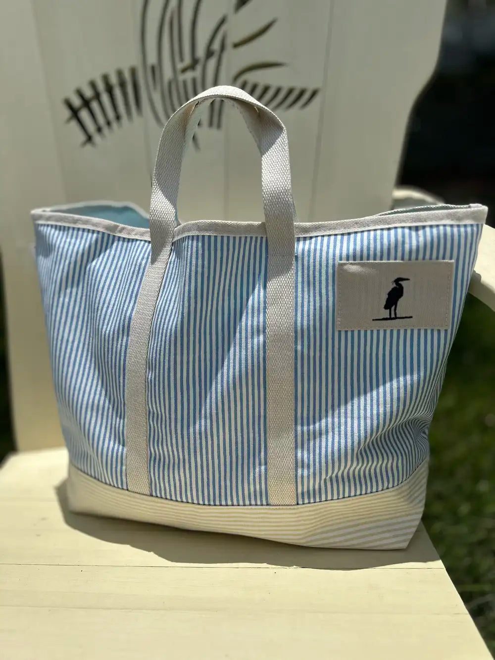 Tote Bag with heron icon stitched on the front. The bag is pinstriped with a pretty blue on white. The bag is made of canvas with sturdy straps. Eastern Shore Style. Boat tote bag, Beach tote bag, everyday bag.