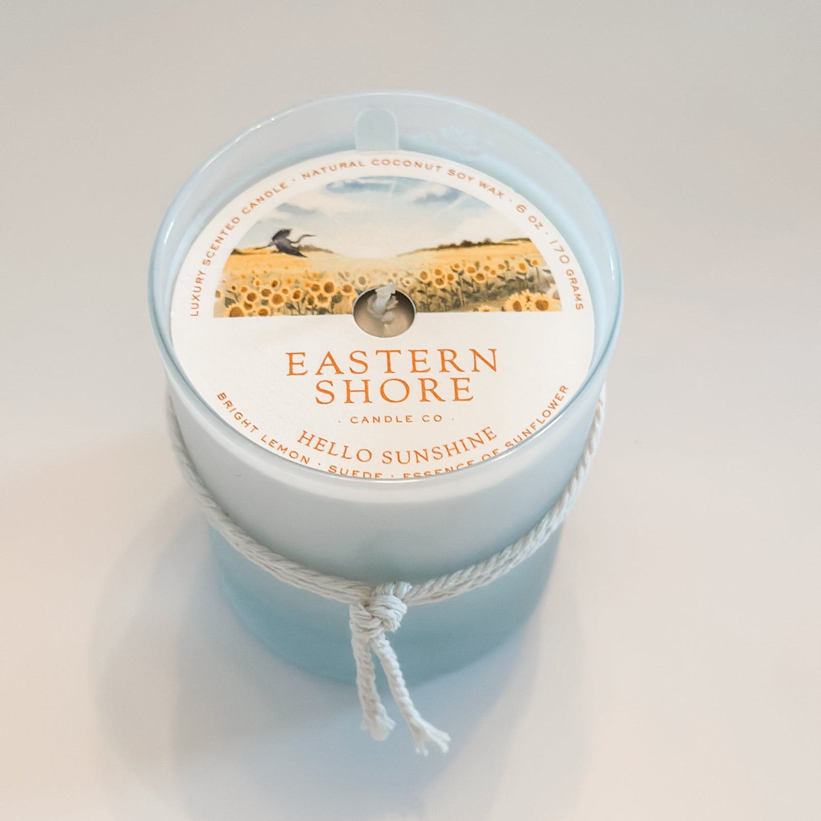Eastern Shore Candle - Hello Sunshine scent in 6oz container against a white background. Inside is a dust cover to protect the candle.